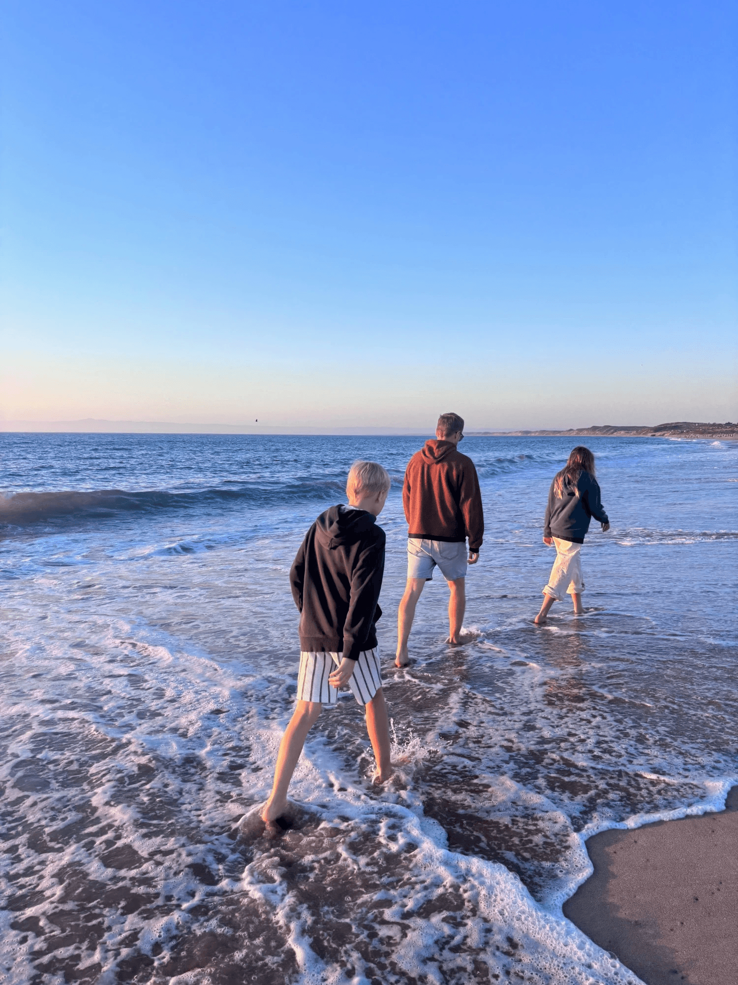 Walking into the ocean at sunset with my two kids.