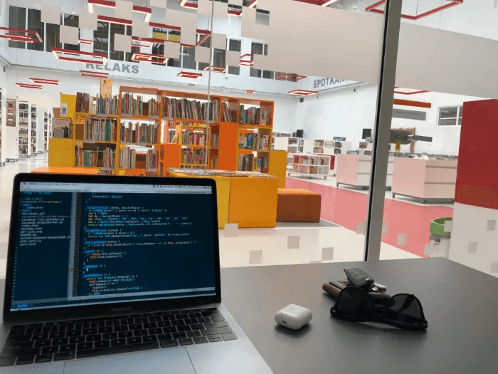 Library, open laptop with a visible code on the screen.